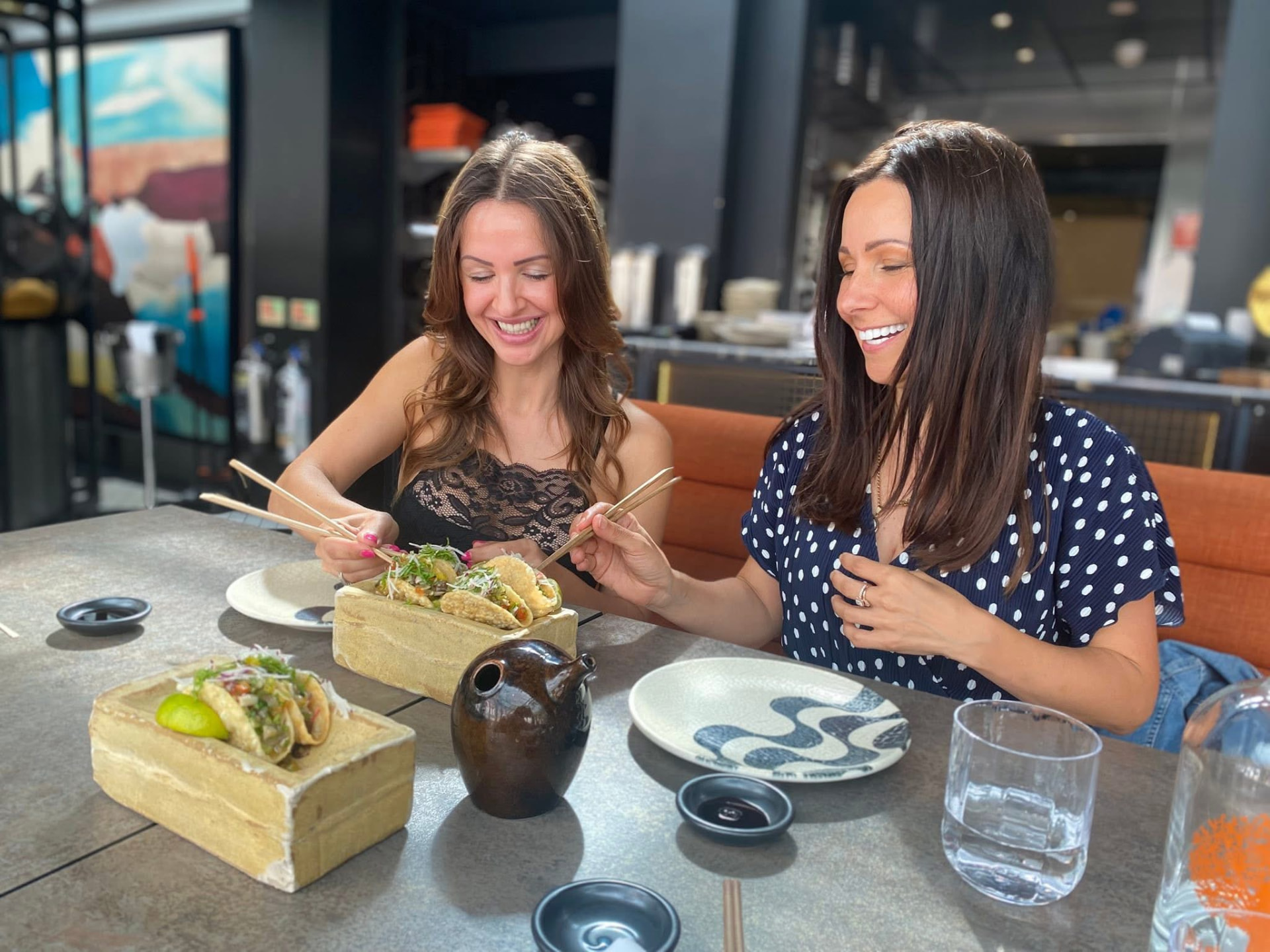Two women sharing tacos at lunch.