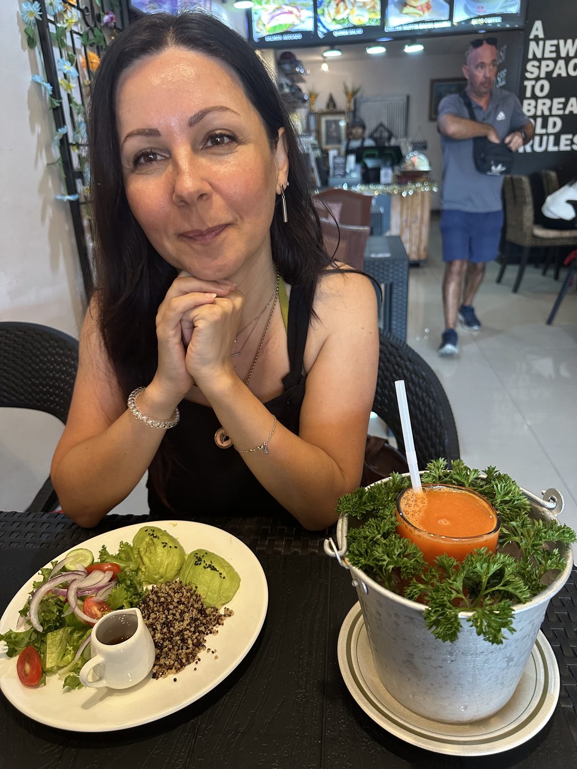 Goreti at a café table with a salad and a fresh juice.